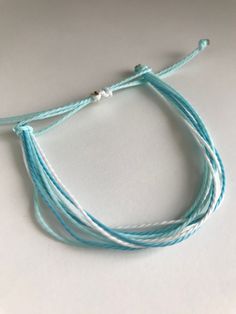 three strands of blue and white string on a white surface with one strand in the middle