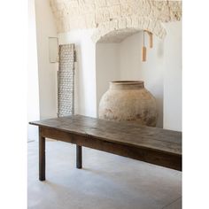 a large vase sitting on top of a wooden table next to a stone arch in a room