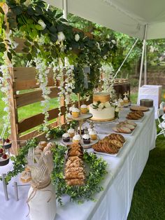 a table topped with lots of desserts and pastries on top of a lush green field