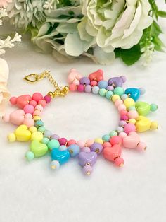 a bracelet with colorful beads and charms on it next to some white flower bouquets