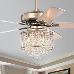 a ceiling fan with crystal chandelier hanging from it's blades in a living room