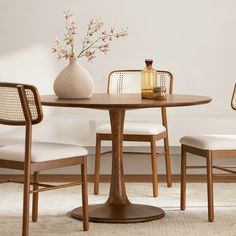 a wooden table with white chairs and a vase filled with flowers on top of it