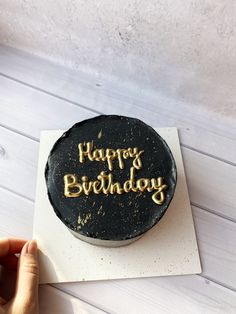 a black and gold birthday cake with the words happy birthday written in gold on it