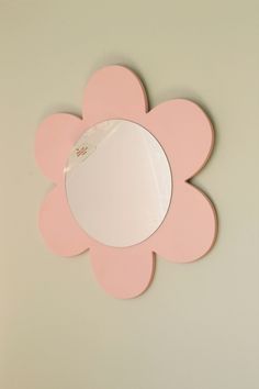 a pink flower shaped mirror hanging on the wall