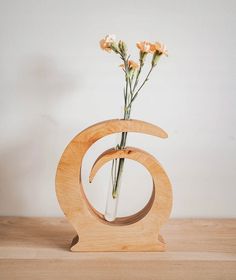 a vase with flowers in it sitting on a wooden table next to a white wall