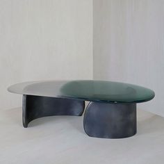 an oval glass table sitting on top of a white floor next to a black chair