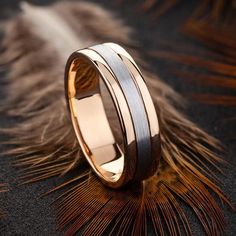 two tone gold and silver wedding band with feathers on the ground in front of it