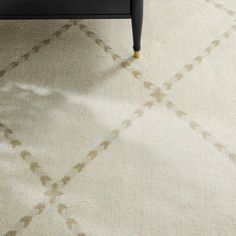 a white rug with brown designs on it and a black coffee table in the background