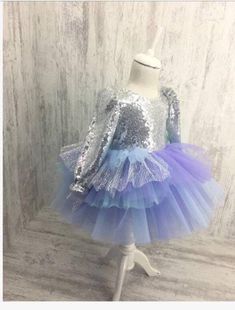 This dress has a silver sequin top and bow and a mermaid colored tutu skirt. Holiday Princess Sequin Dress, Holiday Princess Style Sequin Dress, Princess Style Sequined Tutu Dress For Dress-up, Party Season Sequin Dress With Contrast Sequin, Party Season Contrast Sequin Dress For Dress-up, Holiday Tulle Sequin Dress, Holiday Sequin Tulle Dress, Contrast Sequin Dress For Party Season, Princess Sequin Tutu Dress For Party Season