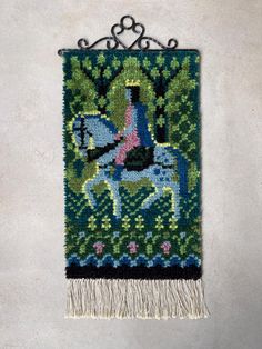 a tapestry hanging on the side of a wall with a horse and rider in it