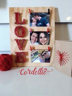 a wooden frame with beaded letters and two photos hanging on the wall next to a red ball of yarn