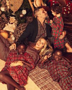 a man and two children are laying on the floor next to a christmas tree with presents