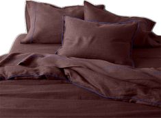 a bed with brown sheets and blue piping on the pillowcase, along with two pillows