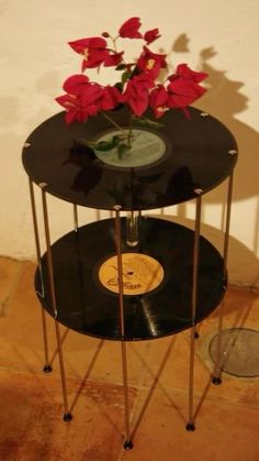 two black tables with flowers on them in front of a wall