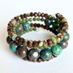 Shades of green, blue, and brown dominate this beaded coil wrap bracelet. Faceted chrysoprase, round jade, and African turquoise come together in a medley of tone and texture in this done-for-you stack. I love the earth tones and contrast of size, color, and texture in this one-of-a-kind bracelet. 4mm round jade 4x5mm faceted chrysoprase 10mm African turqouise one size fits most - best for small to medium wrists Handmade in Lincoln, Nebraska Turquoise Agate Bohemian Bracelets, Bohemian Turquoise Agate Bracelets, Earthy Turquoise Beaded Bracelets With Gemstone Beads, Bohemian Jade Bracelets, Artisan Hand Wrapped Wrap Bracelet With Round Beads, Bohemian Stackable Beaded Bracelets In Turquoise, Bohemian Turquoise Stackable Beaded Bracelets, Stackable Bohemian Turquoise Beaded Bracelets, Handmade Bohemian Jade Bracelets