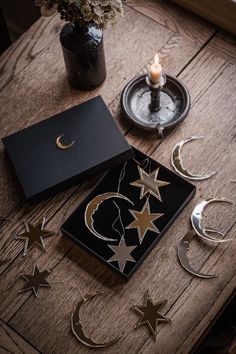 a wooden table topped with metal stars and moon shapes next to a lit candle on top of it