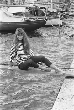 a woman sitting on the edge of a body of water