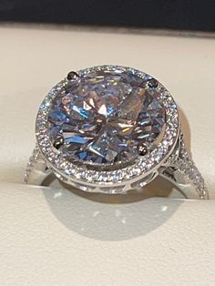 a large diamond ring sitting on top of a white surface with diamonds around it's edges