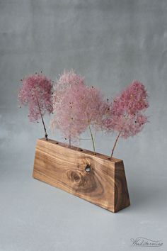 three pink flowers in a wooden vase on a gray background with the word love written below it