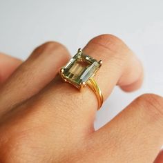 a woman's hand with a ring on it that has an emerald colored stone in the middle