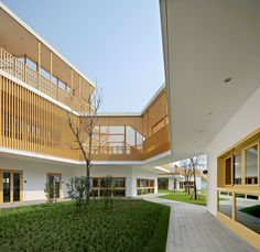 an outside courtyard with grass and trees in the foreground, surrounded by two buildings