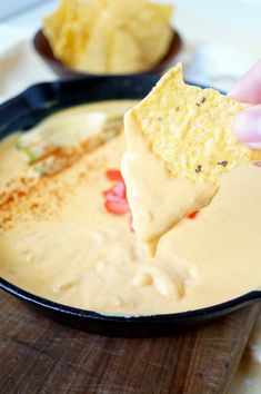 a person dipping tortilla chips into a skillet