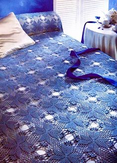 there is a blue crocheted bedspread on the bed