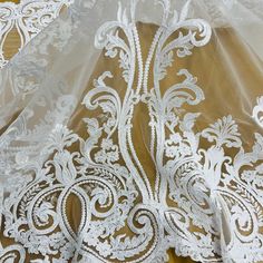 Let the beauty of your special occasion take center stage with our exquisite Beaded & Corded Bridal Lace Fabric Embroidered on 100% Polyester Net Mesh. Featuring the finest beaded and corded French Lace, this exquisite fabric is perfect for crafting elegant wedding dresses, evening gowns, quinceanera dresses, dance costumes and more. This high quality fabric is adorned with embroidery, beads, pearls and sequins and is available in five colors. Our luxurious beaded couture lace, beaded bridal lac Elegant Embroidered White Lace, Elegant White Lace With Intricate Embroidery, White Embroidered Fabric With Lace Trim For Ceremonies, Elegant Embroidered Organza Wedding Dress, Embroidered White Lace For Ceremony, White Embroidered Lace For Ceremony, White Lace With Intricate Embroidery For Ceremonies, White Intricate Embroidered Lace For Ceremony, White Pearl Embroidered Fabric For Mother Of The Bride