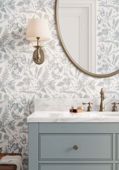 a bathroom vanity with a round mirror above it and a blue cabinet under the sink