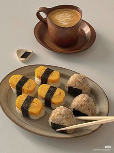 sushi on a plate with chopsticks next to a cup of cappuccino