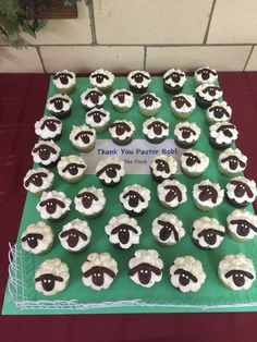 cupcakes with black and white sheep on them sitting on top of a green table