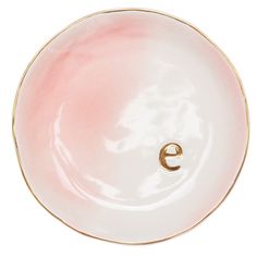 a pink and white plate with a gold letter e in the center on a white background