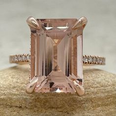 an engagement ring with a large pink diamond in the center on top of a rock