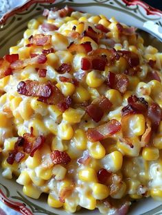 a white plate topped with corn and bacon covered in cheese on top of a table