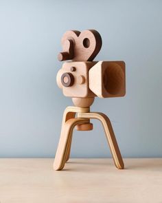 a wooden toy camera sitting on top of a table next to a blue wall,