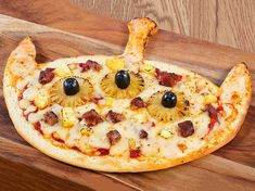 a pizza with pineapple slices and black olives on it is shaped like an animal