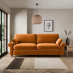 an orange couch sitting on top of a hard wood floor next to a wooden table