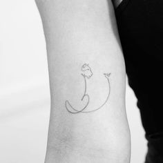 a woman's arm with a small cat tattoo on the left side of her arm