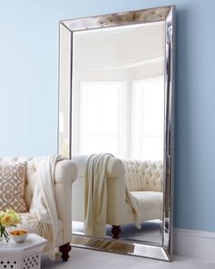 a living room filled with furniture and a large mirror on the wall over a couch