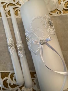 two white candles are sitting next to each other on a lace doily tablecloth