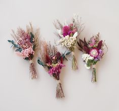 three bouquets of flowers are arranged on a white surface, one is pink and the other is purple