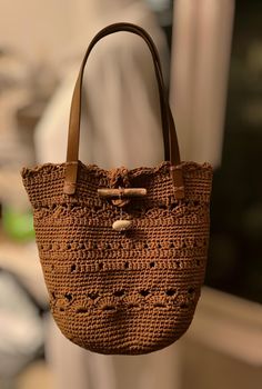 This beautiful retro granny square bag is designed for a unique and stylish look, The bag is hand-knitted with high quality cotton fibers. Beautiful chocolat color ,this crochet bag is perfect for all day use . With an elegant and durable structure, the bag will complement any outfit and highlight your style. For the closure of the bag I placed a small sea wood and a stone from the beach of the city where I live, in Crete, Greece Bag is not lined  . A perfect gift option for your loved ones. Bag Bohemian Brown Bucket Bag With Double Handle, Square Brown Crochet Beach Bag, Bohemian Brown Bucket Bag, Brown Square Crochet Bag For Beach, Bohemian Brown Satchel Straw Bag, Square Brown Crochet Bag For Beach, Bohemian Brown Straw Satchel Bag, Brown Bohemian Bucket Beach Bag, Bohemian Brown Beach Bag With Double Handle