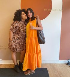 two women standing next to each other in front of a wall with the words you are golden behind them