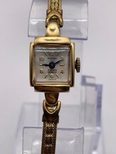 a gold watch sitting on top of a clear display case