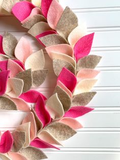 a wreath made out of felt with pink and beige leaves