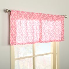 a window with pink and white curtains in front of a window sill on the wall