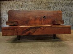 a wooden bench sitting on top of a cement floor next to a brick wall in a building