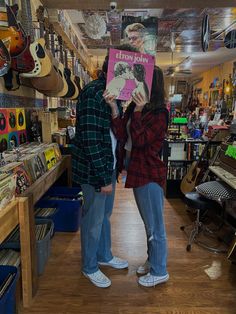 two people standing in a store holding up a book