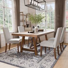 a dining room table with four chairs and a rug on the floor in front of it