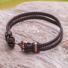 Braided by hand brown leather is used to form two strips that circle the wrist. Thai artisan Passaramon creates this wristband bracelet which exudes strength. It closes with an anchor-shaped clasp of copper-tone stainless steel. Adjustable Brown Copper Braided Bracelets, Adjustable Brown Leather Bracelet With Wrist Strap, Brown Leather Strap Wristband, Adjustable Brown Wristband With Bracelet Strap, Adjustable Brown Leather Wristband, Adjustable Brown Leather Braided Bracelet, Brown Leather Strap Bracelet, Adjustable Brown Leather Sweatband Wristband, Adjustable Double Band Brown Wrap Bracelet